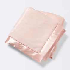 two pink blankets folded on top of each other with satin trimming around the edges