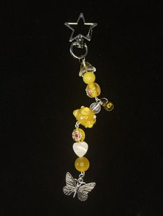 a yellow beaded keychain with butterfly charms on it's side and a star hanging from the back