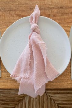 a white plate with a pink napkin on top of it next to silver utensils