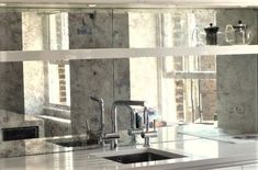 a kitchen sink sitting under a mirror next to a stove top oven and countertop