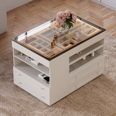 a white coffee table with drawers and a flower on the glass top in front of a wooden floor