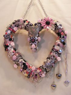 a heart made out of many different types of buttons and charms hanging on a chain