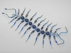 a group of blue and silver wires on a white surface with beads attached to them