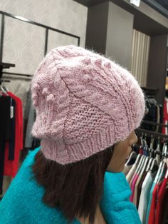 a mannequin wearing a pink knitted hat in a clothing store with clothes on racks