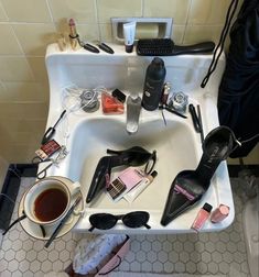 a bathroom sink filled with lots of different types of cosmetics and other personal care items