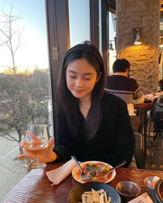 a woman sitting at a table with plates of food and wine in front of her