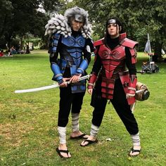 two people dressed up in costumes standing on the grass with swords and armor around their necks