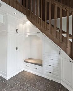 an open closet under the stairs in a house with white cabinets and drawers on either side