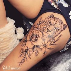 a woman's thigh with a leopard and roses tattoo on it, sitting next to a teddy bear