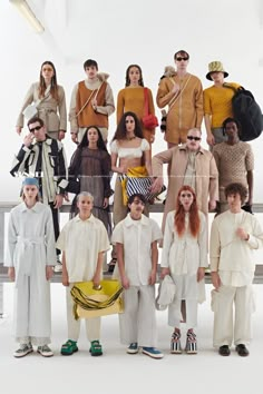 a group of people standing next to each other in front of a white wall wearing different colored clothing