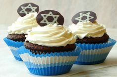 two cupcakes with white frosting and chocolate decorations on top are sitting next to each other