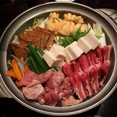 a metal bowl filled with meat and vegetables