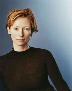 a woman with red hair is posing for a photo in front of a blue background