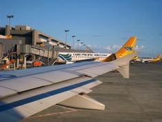 the wing of an airplane is shown with many other planes parked in the back ground