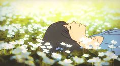 a woman laying in the grass with daisies on her chest and eyes closed,