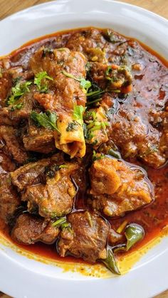 a white plate topped with meat covered in sauce and garnished with parsley