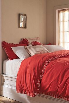 a bed with red sheets and pillows in a room