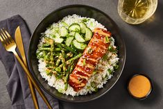 a black plate topped with rice, asparagus and salmon