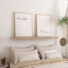 two framed pictures on the wall above a bed with white linens and pillows in a bedroom