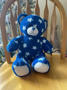 a blue and white teddy bear sitting on top of a wooden chair