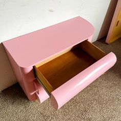 a pink desk with two drawers on the bottom and one drawer open to show what's inside