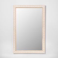 a white and gold framed mirror on a wall with an intricate border around the frame