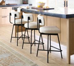 three barstools sit in the middle of a kitchen with an area rug on the floor