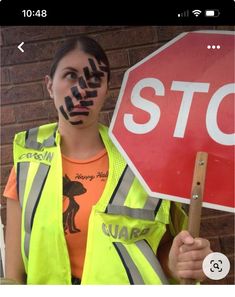 a woman holding a stop sign painted on her face