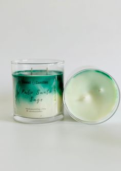 a green candle sitting next to a glass container on a white surface with the lid open