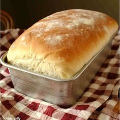 a loaf of bread in a tin on a checkered cloth