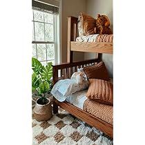 a bedroom with bunk beds and pillows on the bottom bed, next to a potted plant