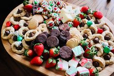 a wooden platter filled with assorted cookies and candy bars on top of a table