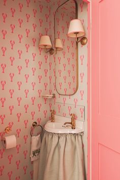 a bathroom with pink wallpaper and gold fixtures