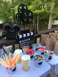 a table topped with cups filled with candy next to a movie clapper and film reel