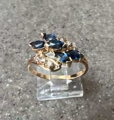 Stunning 14K Yellow Gold Blue Sapphire & Diamond Cocktail Ring! This gorgeous ring weighs 2.5 Grams.  It's a size 7.25 and is marked 14K inside. The blue sapphires and diamonds create a lovely, large, eye catching design.  Five Marquis sapphires, all with a stunning shade of dark blue, make up the center of the ring. Six sparkly diamonds, in two separate rows, surround the sapphires. The ring is in excellent condition. Stock # S808 Will ship in a gift box As with all jewelers, I do enlarge pictu Vintage Sapphire Gold Ring, Vintage 14k Gold Sapphire Ring With Polished Finish, Luxury Vintage Sapphire Ring With Polished Finish, Vintage Yellow Gold Sapphire Ring For Gift, Antique Gold Sapphire Ring Hallmarked, Vintage Multi-stone Sapphire Ring In 14k Gold, Shades Of Dark Blue, Sapphire Cocktail Ring, Diamond Cocktail Ring