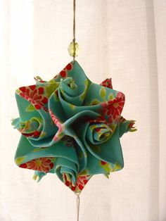 an ornament made out of fabric with flowers on it hanging from a string