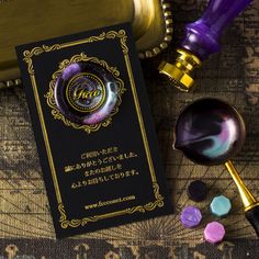 a purple and gold business card next to some other items on top of a table