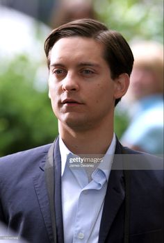 a man in a suit and tie looking off to the side with people behind him