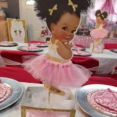 a table set up with pink and gold plates, napkins, and paper cutouts