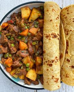 two pita breads on a plate with meat and vegetables next to each other