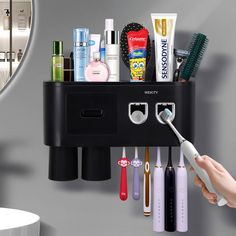 a person is holding an electric toothbrush in front of a wall mounted holder with many different items on it