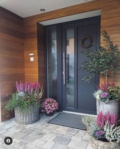 some plants are sitting in front of a door and two baskets with flowers on them