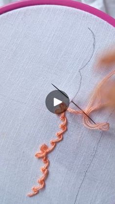 someone is stitching an orange thread on a piece of fabric that has been sewn