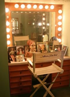 a chair sitting in front of a vanity with a mirror and lights on it's sides