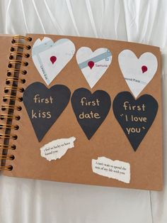 a brown notebook with black and white heart stickers on the pages that read first kiss, i love you