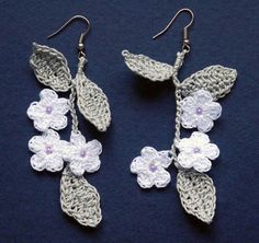 crochet earrings with white flowers on them are hanging from silver earwires