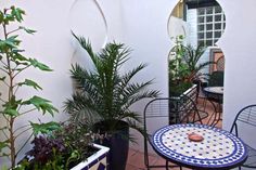 an outdoor patio area with potted plants and tables on the ground, along with mirrors