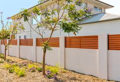 a white house with wooden slats on the fence and trees in front of it