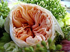 an arrangement of flowers is displayed on a table with green leaves and pink carnations