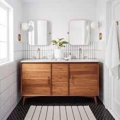 a bathroom with black and white flooring and wooden cabinetry, along with two mirrors on the wall